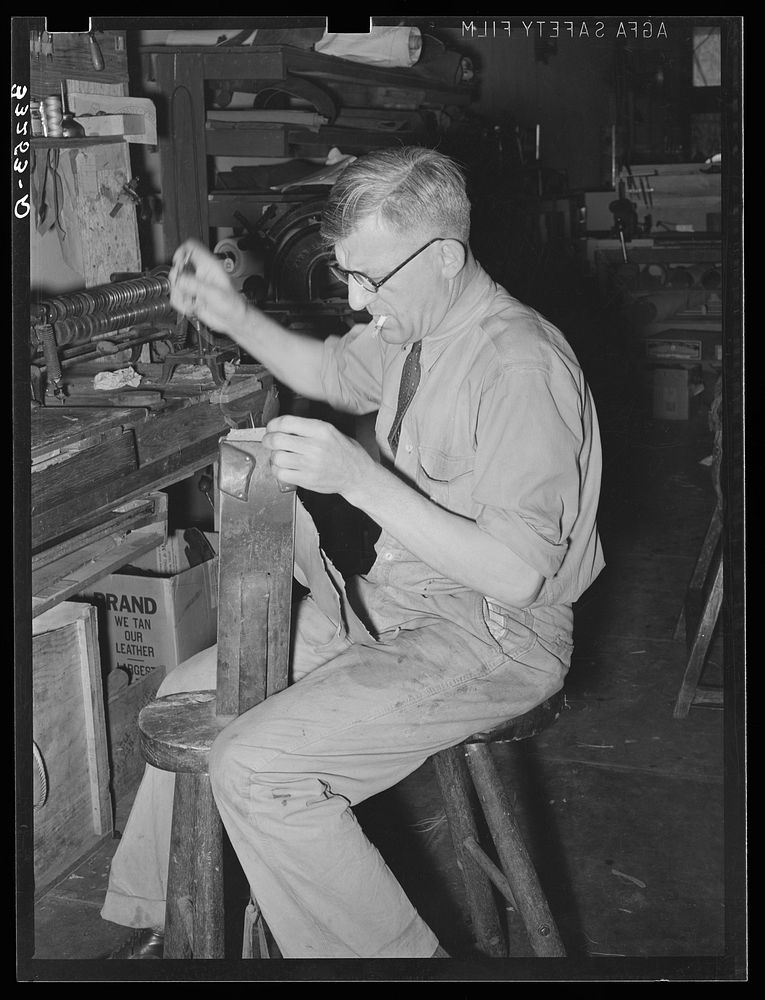 Sewing pieces of leather together on saddle maker's bench. Saddle shop, Alpine, Texas by Russell Lee