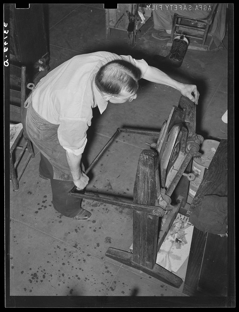 Crimping is accomplished by pulling down the lever on the crimping machine. Bootmaking shop, Alpine, Texas by Russell Lee