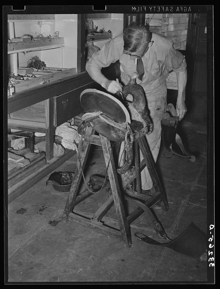 Saddle maker applying cement to glue parts of saddle together. Saddle shop, Alpine, Texas by Russell Lee