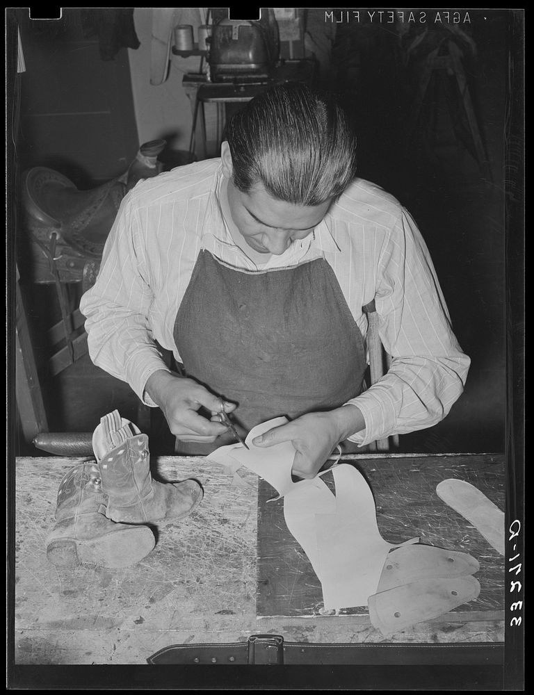Cutting pieces of leather to repair child's cowboy boots. Saddle shop, Alpine, Texas by Russell Lee