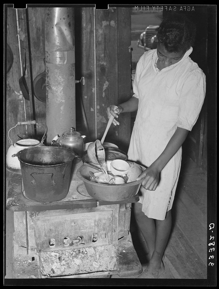 Daughter of  agricultural day laborer washing dishes in her home in Muskogee County, Oklahoma by Russell Lee