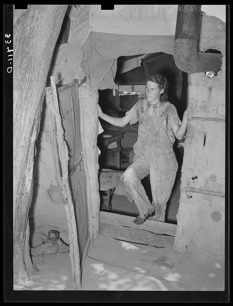 Woman agricultural day laborer standing in the doorway of her tent home.  Near Webbers Falls, Oklahoma. Muskogee County by…