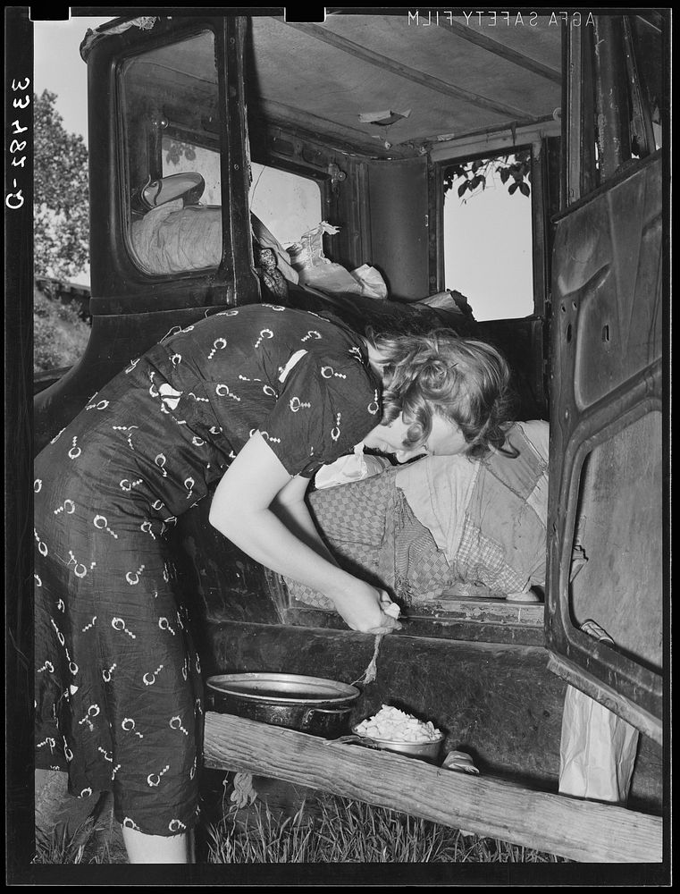 Migrant woman peeling potatoes on running board of car while camped near Prague, Oklahoma. Lincoln County, Oklahoma by…