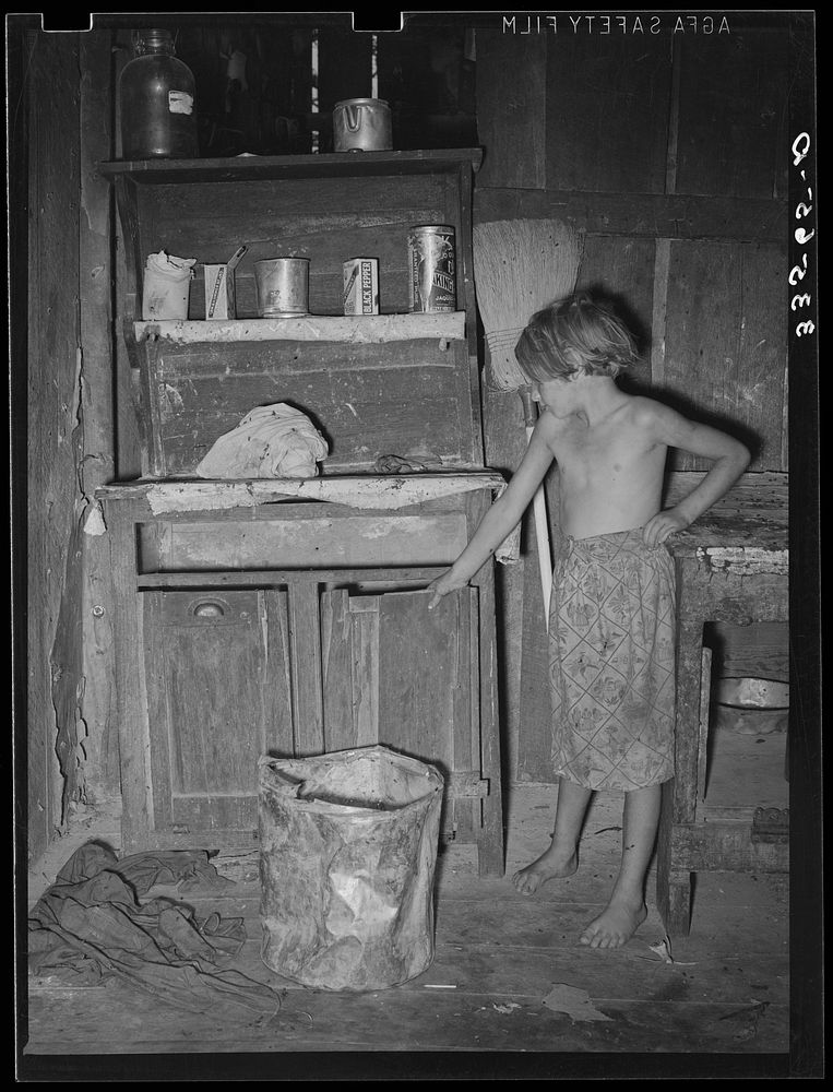Daughter of day laborer in front of kitchen cabinet. McIntosh County, Oklahoma by Russell Lee