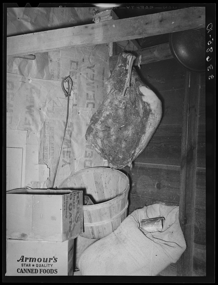 Side of bacon hanging from rafter and sack of flour in tenant farm home near Sallisaw, Oklahoma by Russell Lee