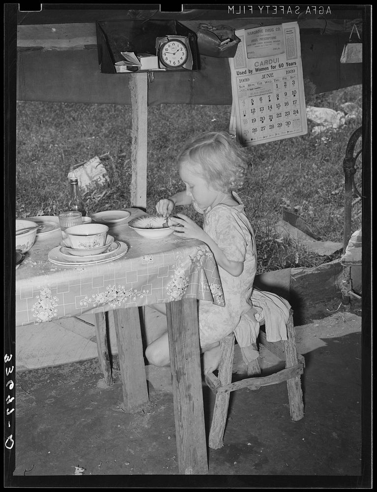 Daughter of day laborer eating lunch in tent home near Spiro, Oklahoma. Sequoyah County by Russell Lee