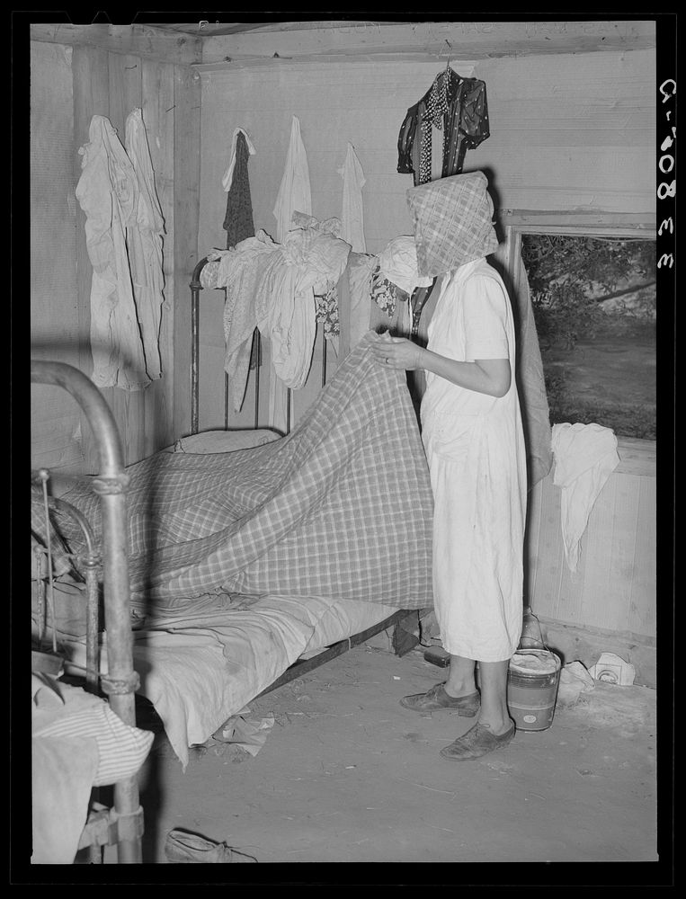 Removing bedclothing from house, preparatory to packing for departure to California from Muskogee, Oklahoma by Russell Lee