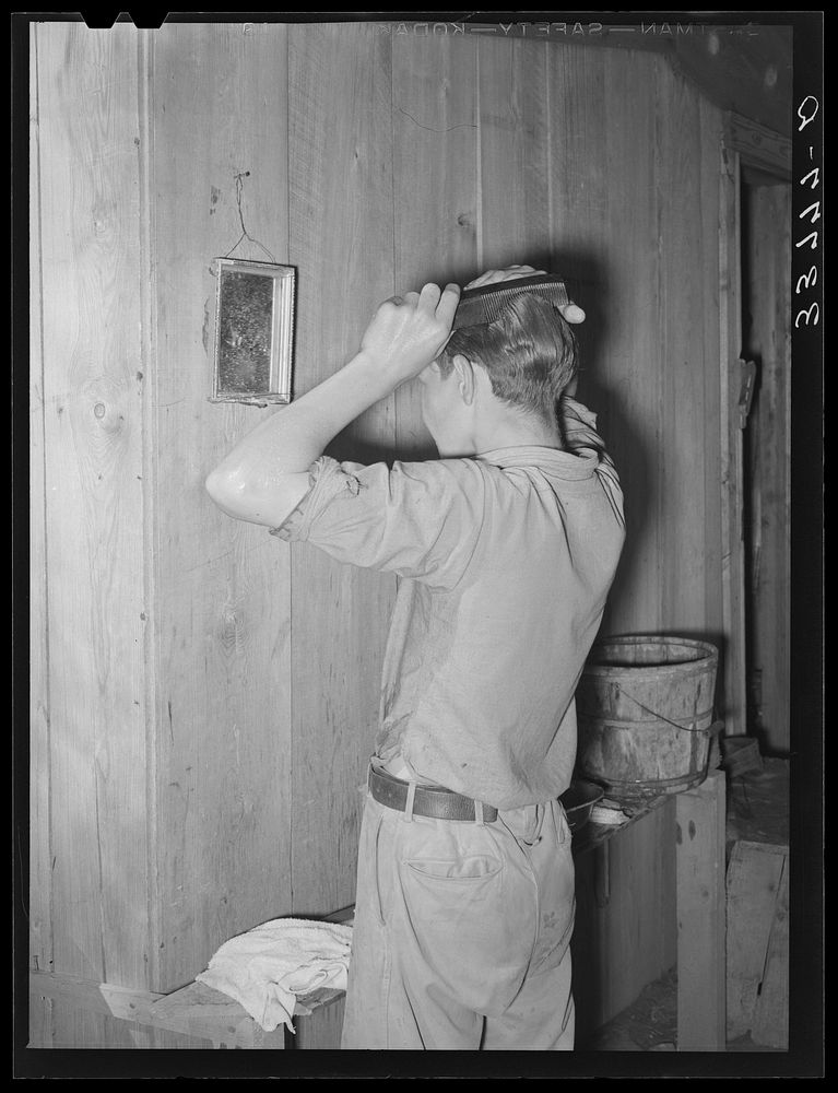Migrant boy combing his hair at his home near Muskogee, Oklahoma by Russell Lee