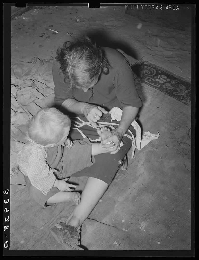 Mother of child pointing to his cut toe, injured while playing in trash and debris of camp. Mays Avenue camp, Oklahoma City…