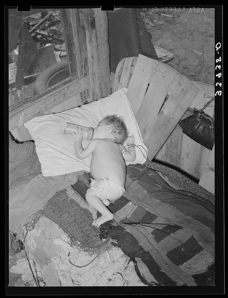 Baby with his bottle in shack home near Mays Avenue camp. Oklahoma City, Oklahoma. See general caption no. 21 by Russell Lee