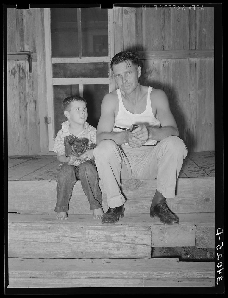 Oil field truck driver and his son sitting on front porch. Seminole, Oklahoma by Russell Lee