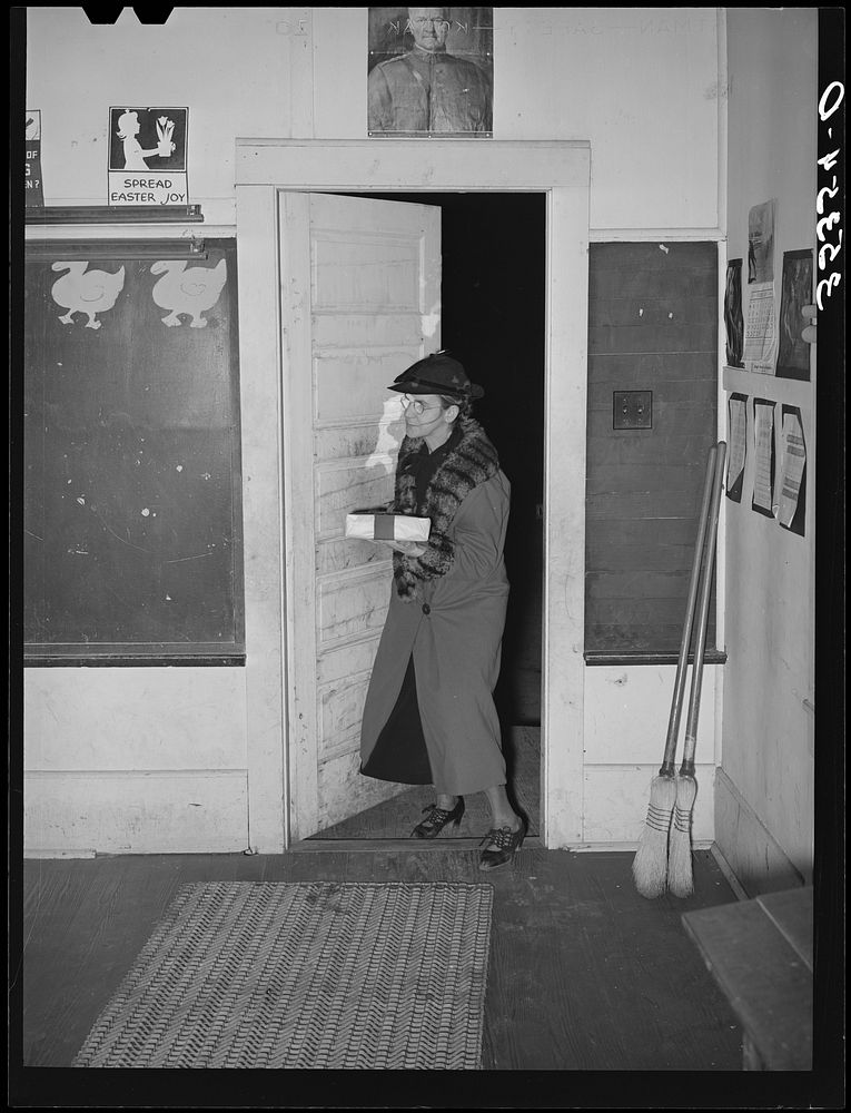 Elderly farm woman arriving at pie supper with her pie which will be sold at auction. Muskogee County, Oklahoma. See general…