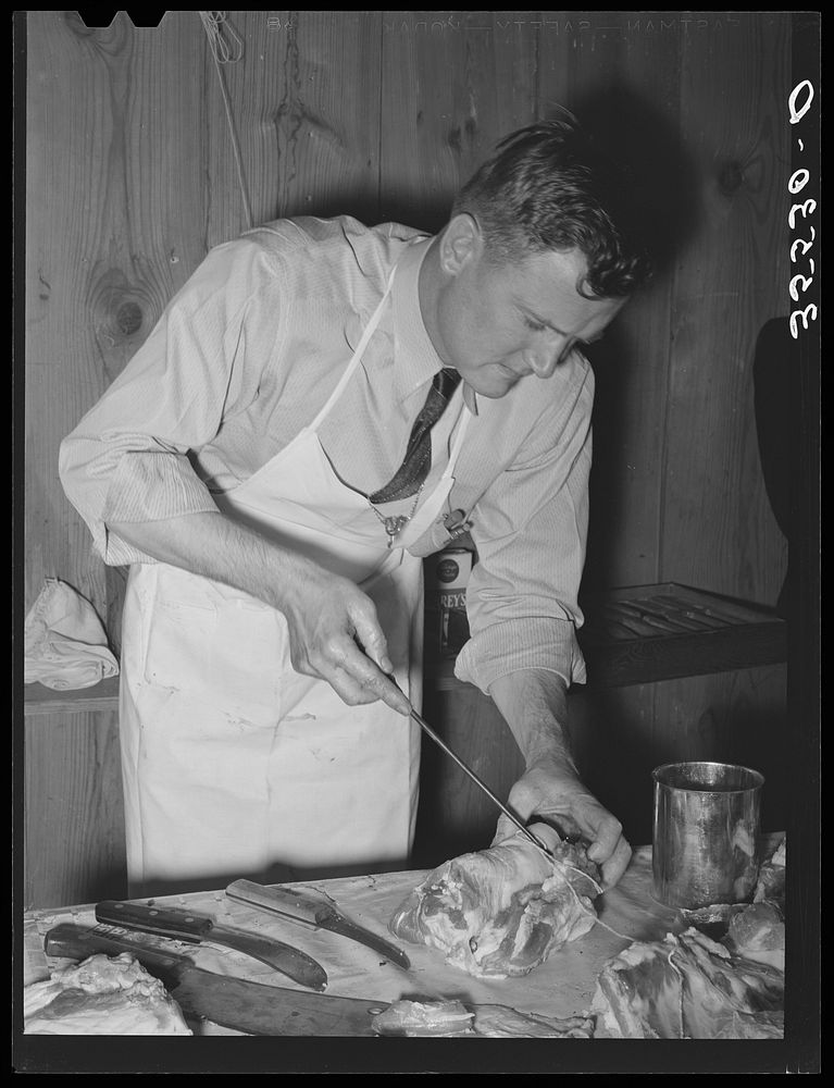 FSA (Farm Security Administration) supervisor sewing up a pork rolled roast during a meat cutting demonstration before a…