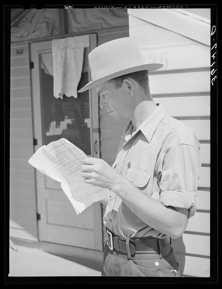 Migratory agricultural worker reading instructions on how to obtain a license to operate a truck. Agua Fria migratory labor…