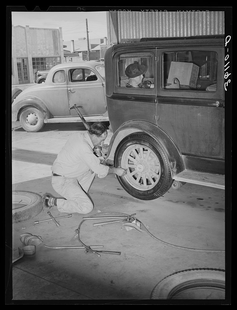 [Untitled photo, possibly related to: Changing a tire at the United Producers and Consumers Cooperative service station.…