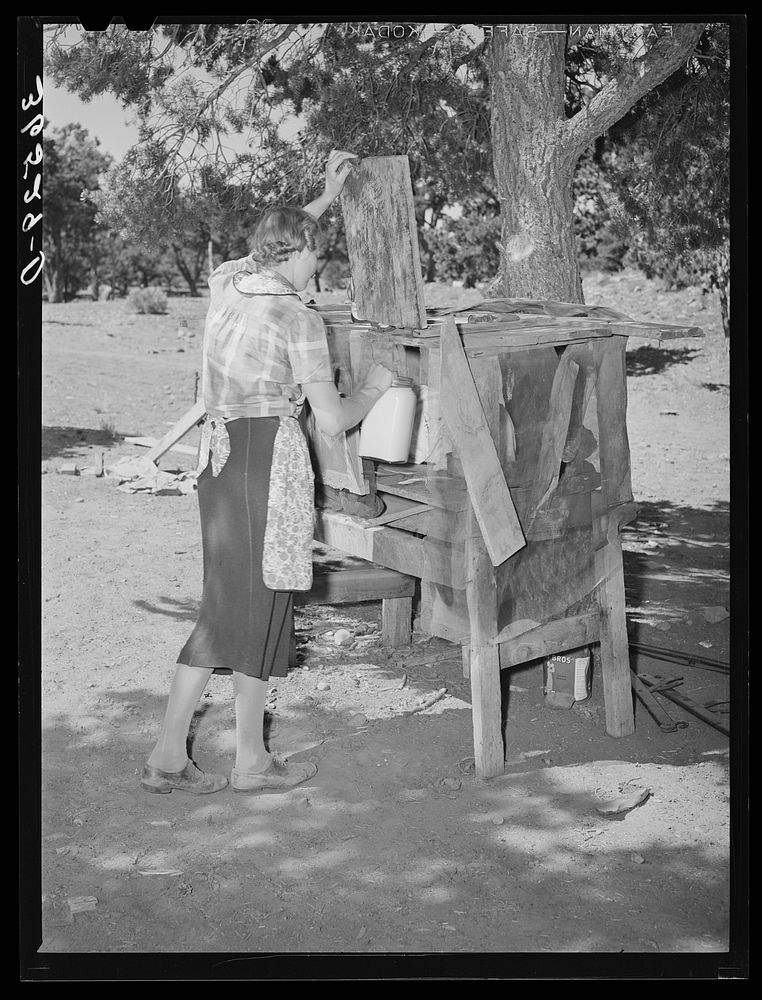 Mrs. Faro Caudill placing milk into homemade cooling box. Damp cloths are wrapped around buckets and jars of milk, and rapid…