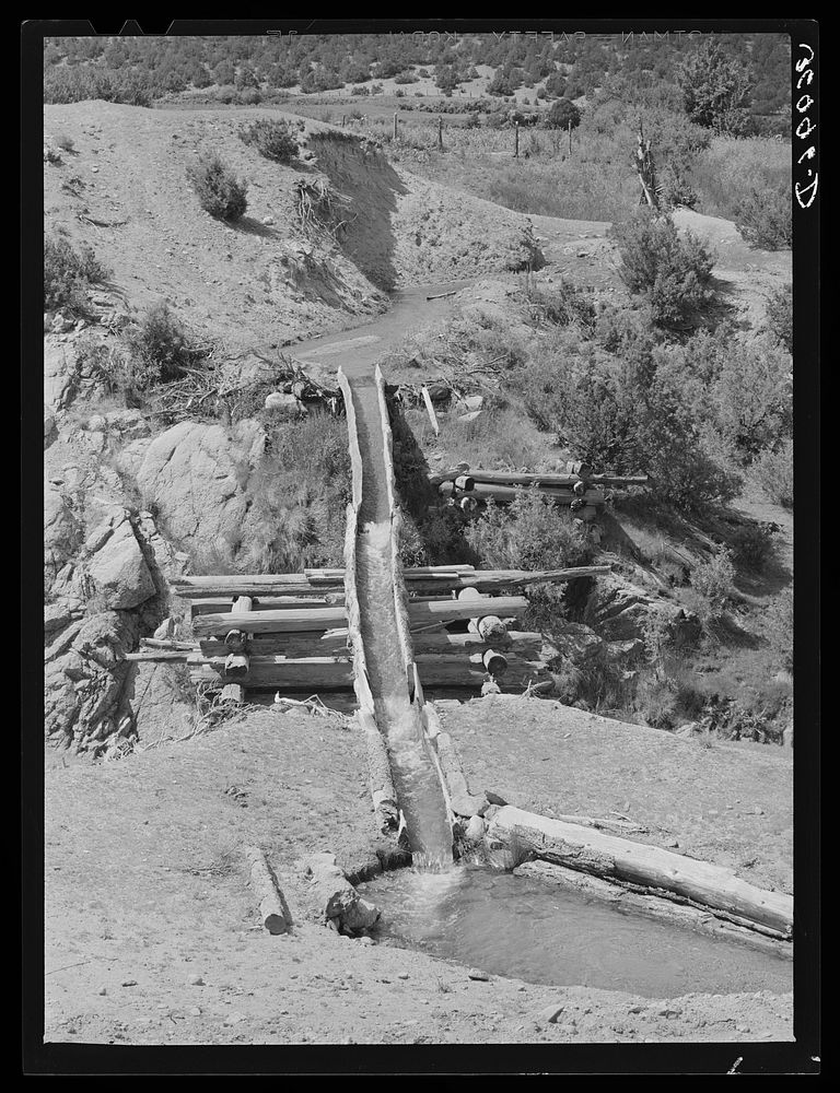 Hollowed-out logs used for transporting irrigation waters across ditch. Trampas, New Mexico by Russell Lee