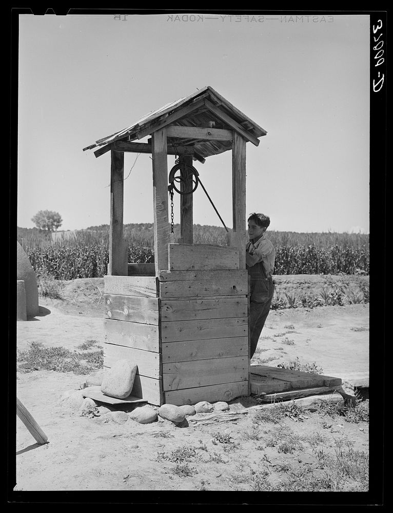 Spanish-American boy drawing water from well. Chamisal, New Mexico by Russell Lee