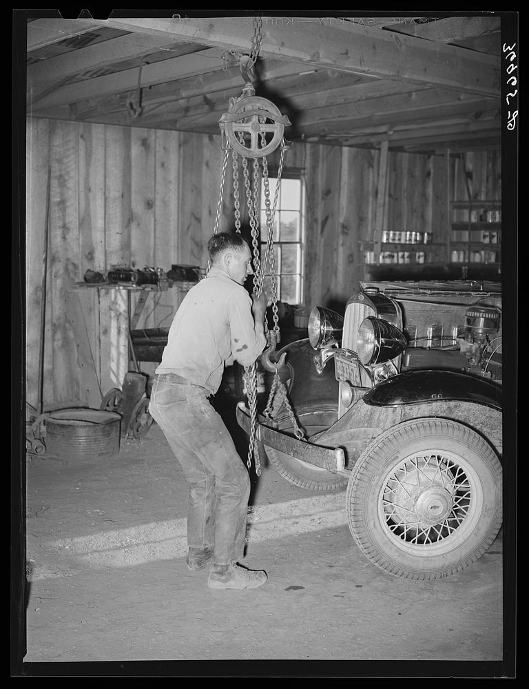 Garage owner hoisting car so that he can make repairs. Pie Town, New Mexico by Russell Lee