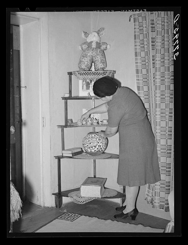 Wife of local merchant arranging bric-a-brac in her home. Concho, Arizona by Russell Lee