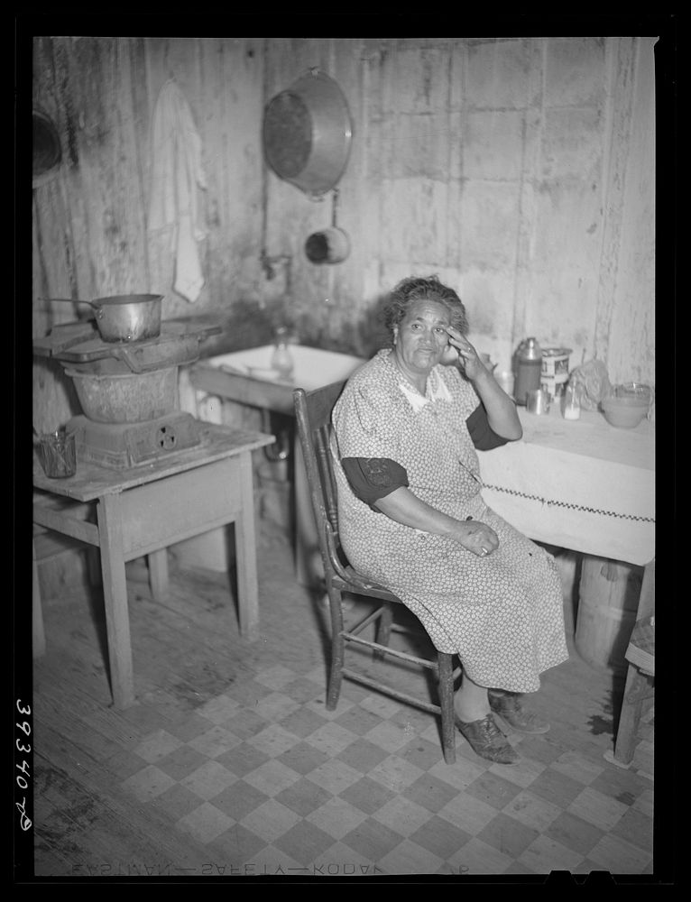 [Untitled photo, possibly related to: Mexican woman at table in kitchen of her two-room house. San Diego, California] by…