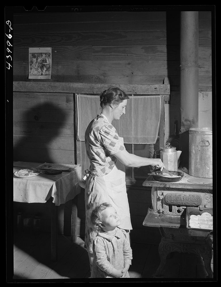 Mrs. Lemuel Smith preparing the afternoon meal on her farm in Carroll County, Georgia (see general caption). Sourced from…