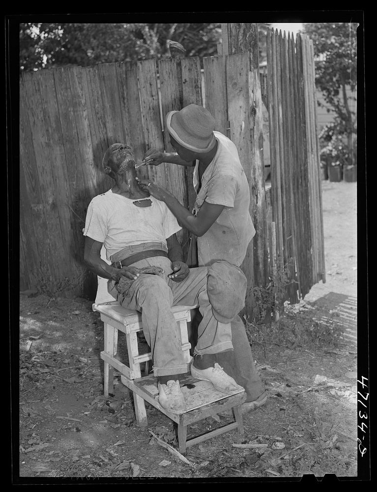 Charlotte Amalie, Saint Thomas Island, Virgin Islands. An outdoor barber shop in a slum area near the waterfront. Sourced…