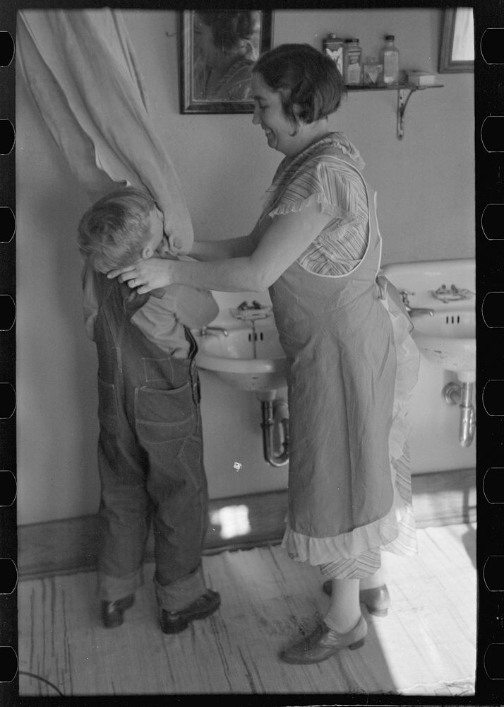 Mrs. Rustan combing her young son's hair. Rustan brothers' farm, Dickens, Iowa. Note running water by Russell Lee
