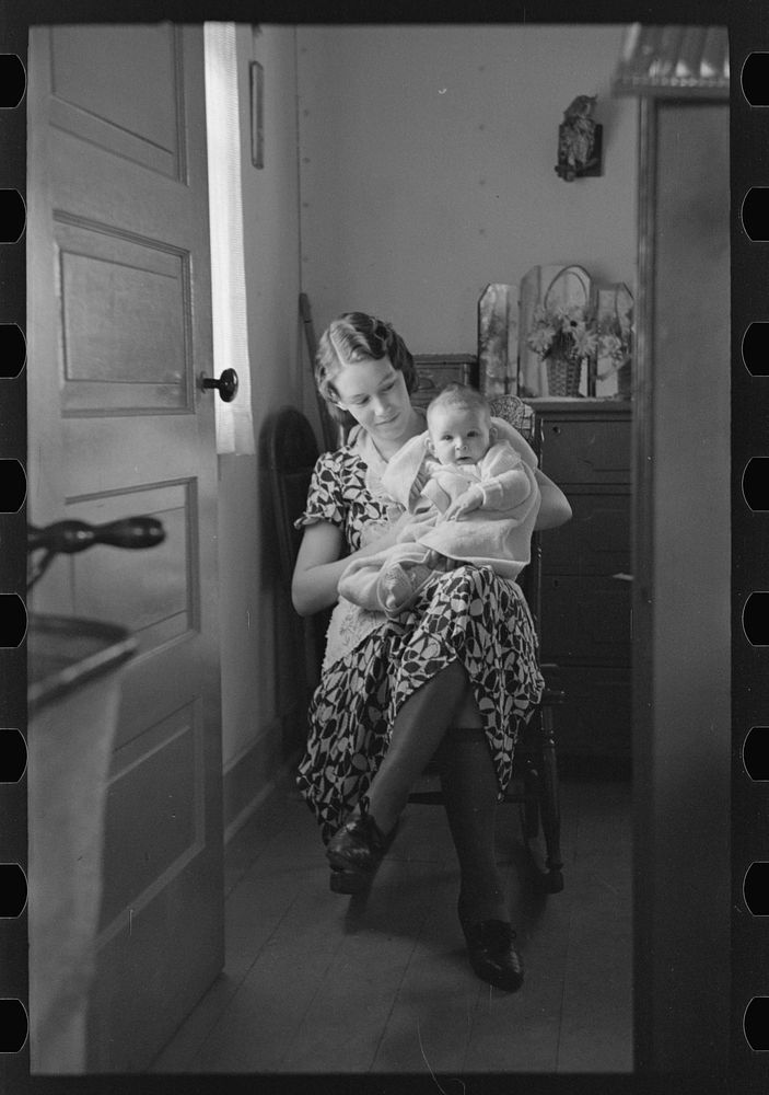 [Untitled photo, possibly related to: Child on lap of mother reading the newspaper. Nissen shack near Dickens, Iowa] by…