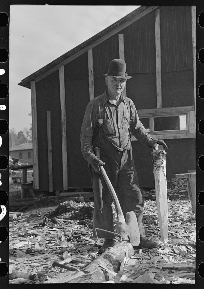 Lumberjack with stake which he has been shaping with broadaxe, at camp near Effie, Minnesta by Russell Lee