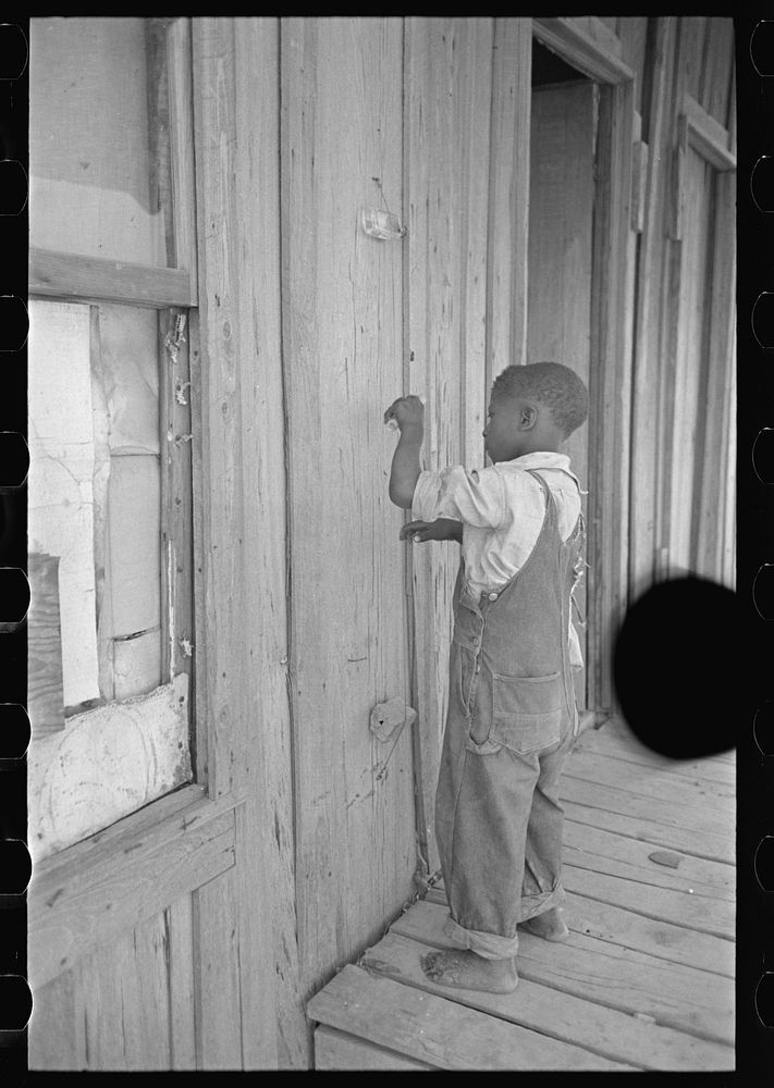 [Untitled photo, possibly related to: Child of former sharecropper, playing primitive musical instrument made by stretching…