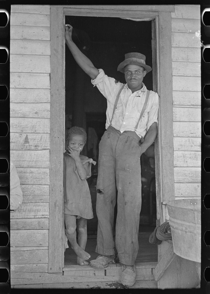 Sharecropper and young daughter standing in doorway of shack home. New Madrid County, Missouri by Russell Lee