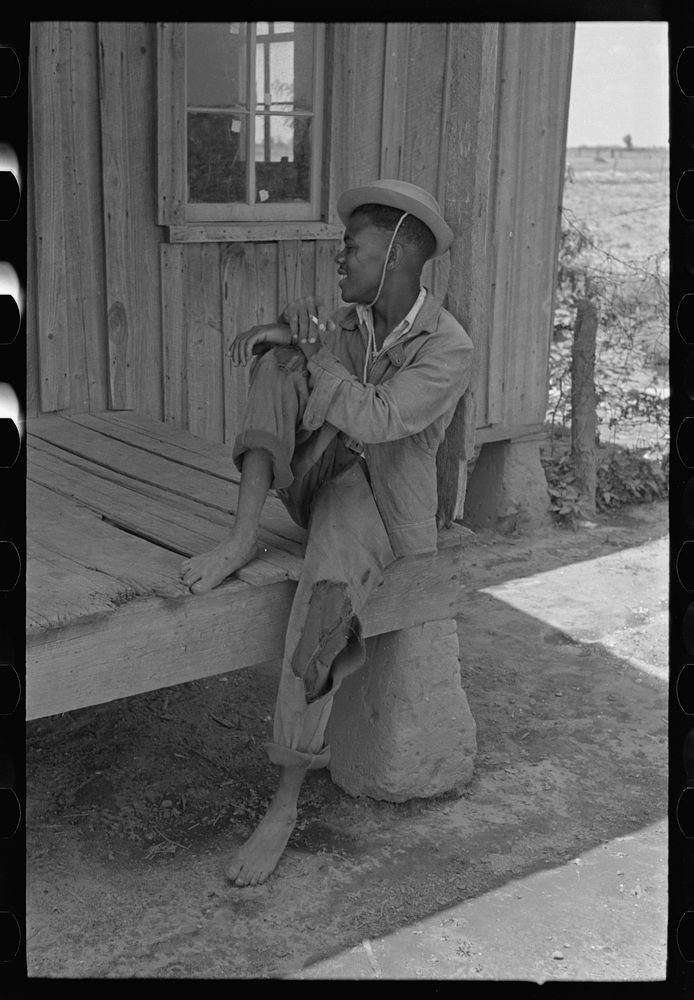 Son of sharecropper sitting on front porch of shack home, New Madrid County, Missouri by Russell Lee