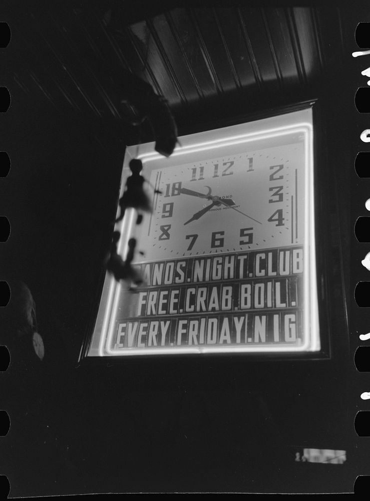 Illuminated clock in Raceland, Louisiana, saloon. Note advertisement of crab boil by Russell Lee