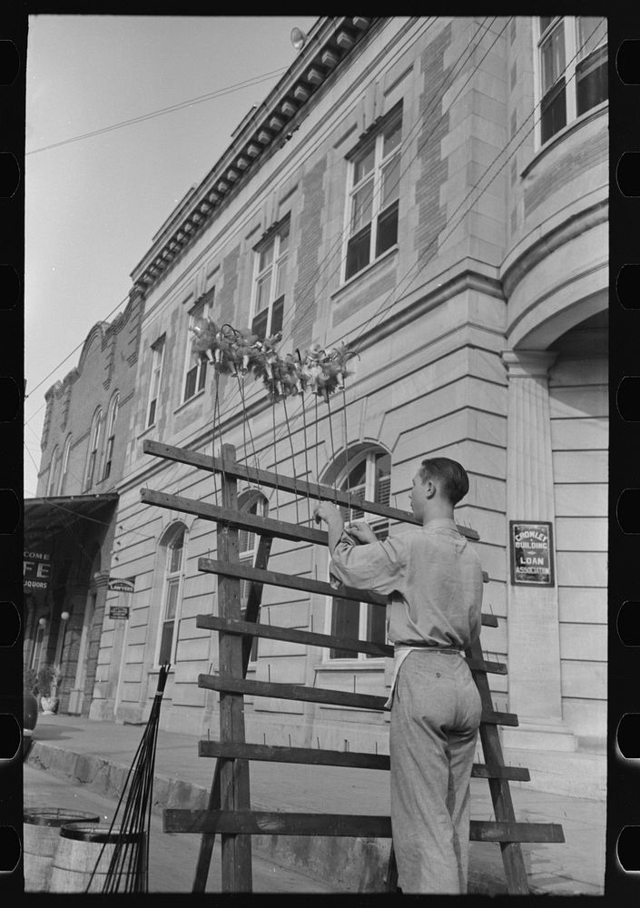 [Untitled photo, possibly related to: Concessionaire placing doll canes in rack, National Rice Festival, Crowley, Louisiana]…