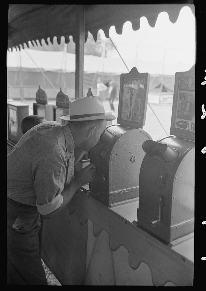 Man looking through penny peep show, state fair, Donaldsonville, Louisiana by Russell Lee