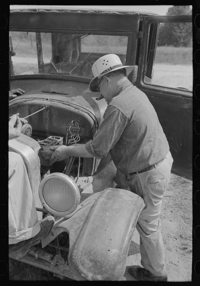 Junkyard owner working on automobile of farmer near Abbeville, Louisiana by Russell Lee
