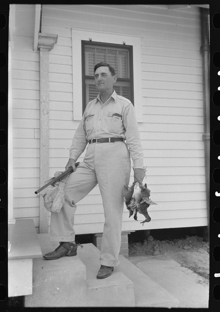 [Untitled photo, possibly related to: Joseph La Blanc, wealthy Cajun farmer, standing on steps of home with birds from a…