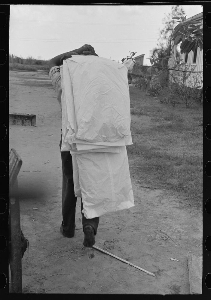 Carrying dry cleaned articles to store from boat, Burrwood. Articles to be cleaned must be sent to New Orleans by Russell Lee