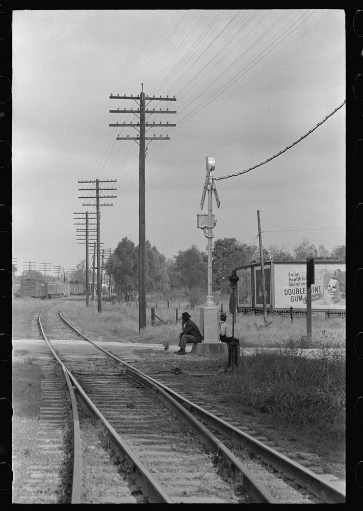 Men sitting on signal tower beside railroad track, Morgan City, Louisiana by Russell Lee