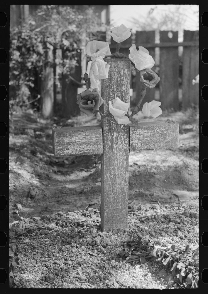 Decorated headstone in cemetery, New Roads, Louisiana on All Saints' Day. Artificial flowers are made of paper by Russell Lee