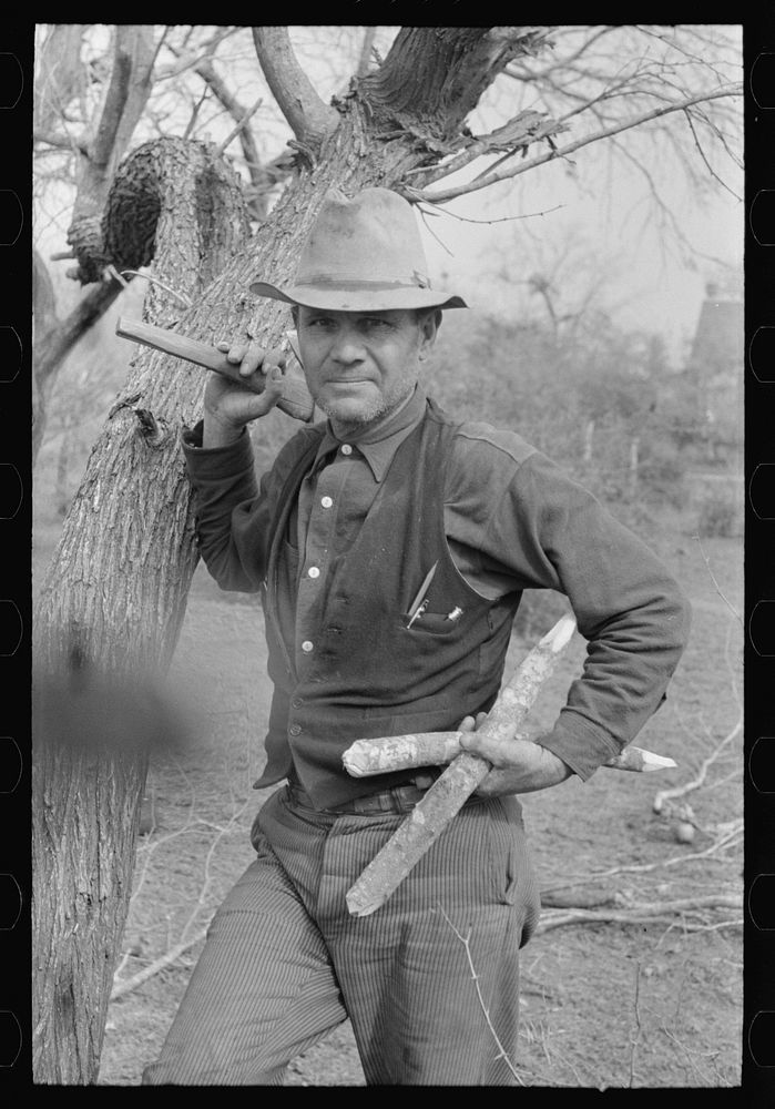 White migrant worker with hatchet and stakes to be used in setting up new camp near Harlingen, Texas by Russell Lee