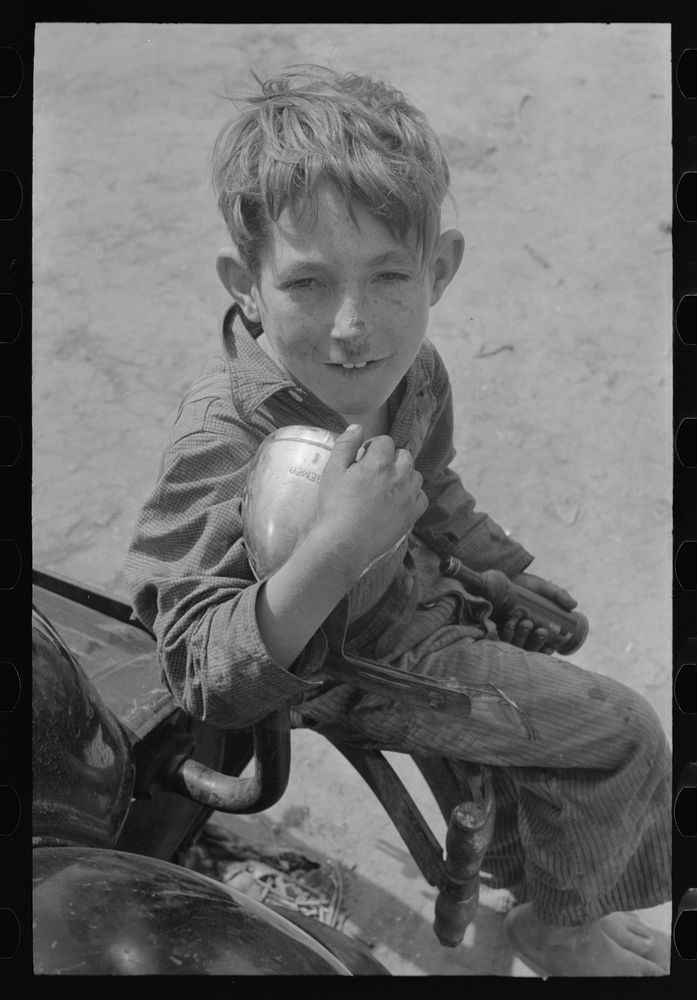 Son of migrant sitting on rear bumper of automobile, north of Harlingen, Texas by Russell Lee