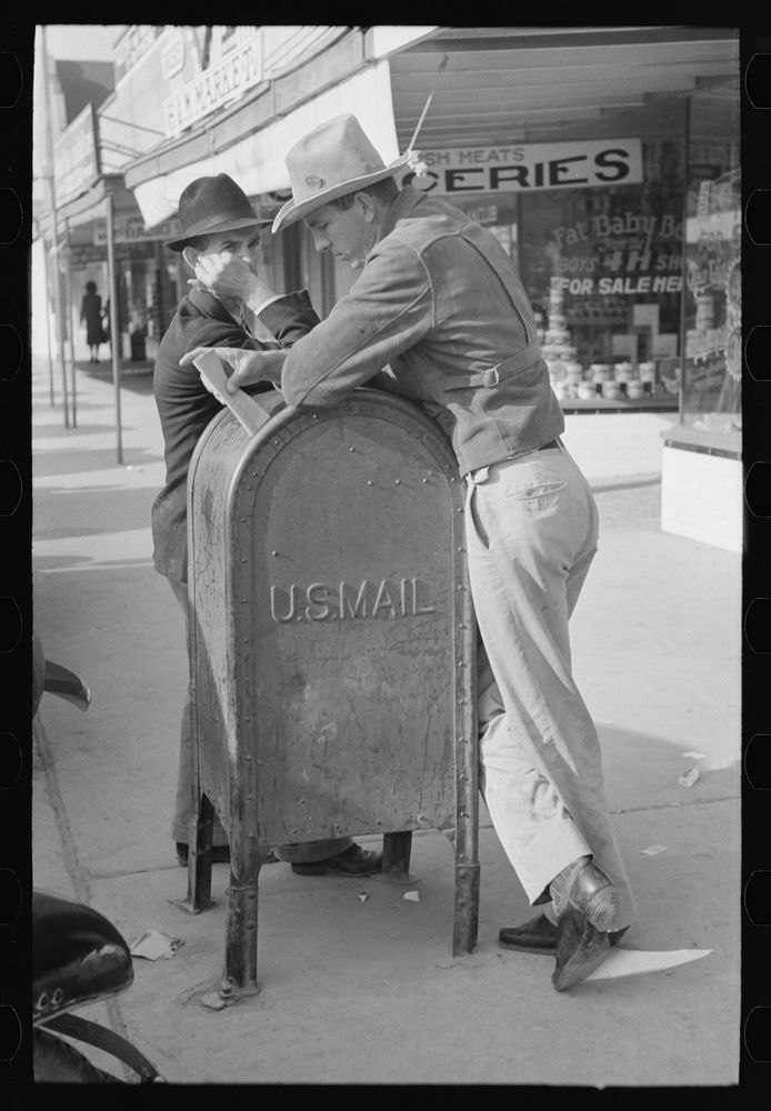 Men leaning on mailbox, Crystal City, Texas by Russell Lee
