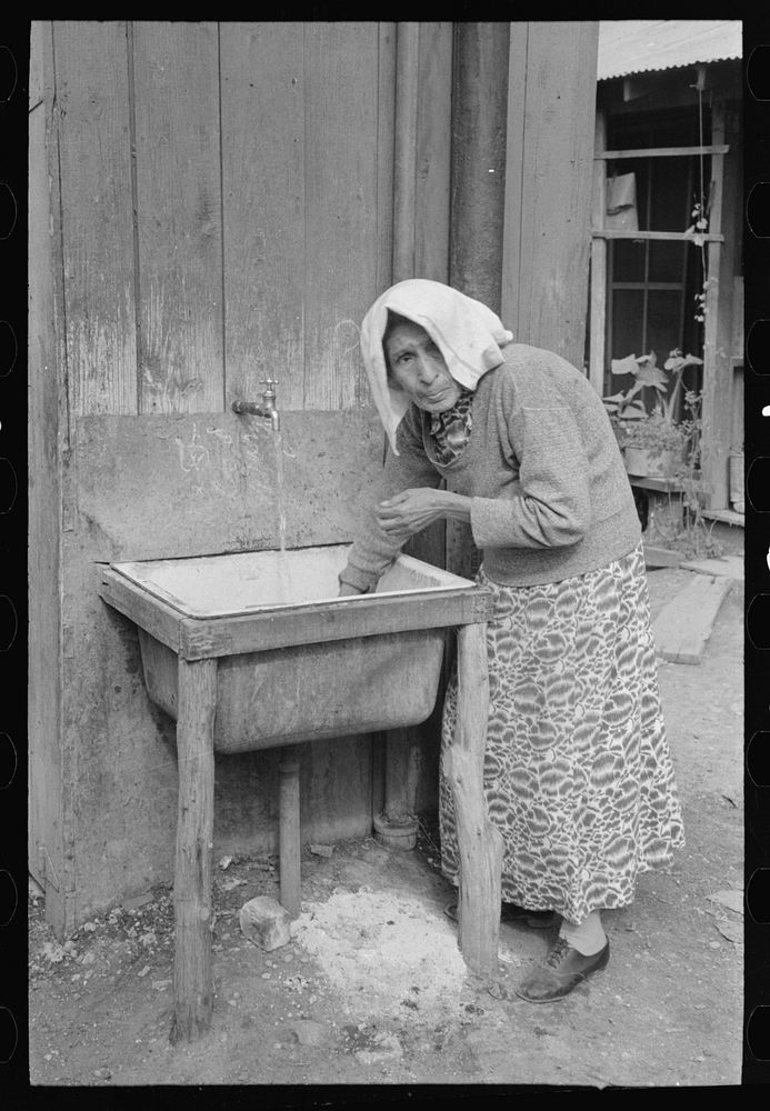 Old Mexican woman drawing water at community hydrant, San Antonio, Texas by Russell Lee