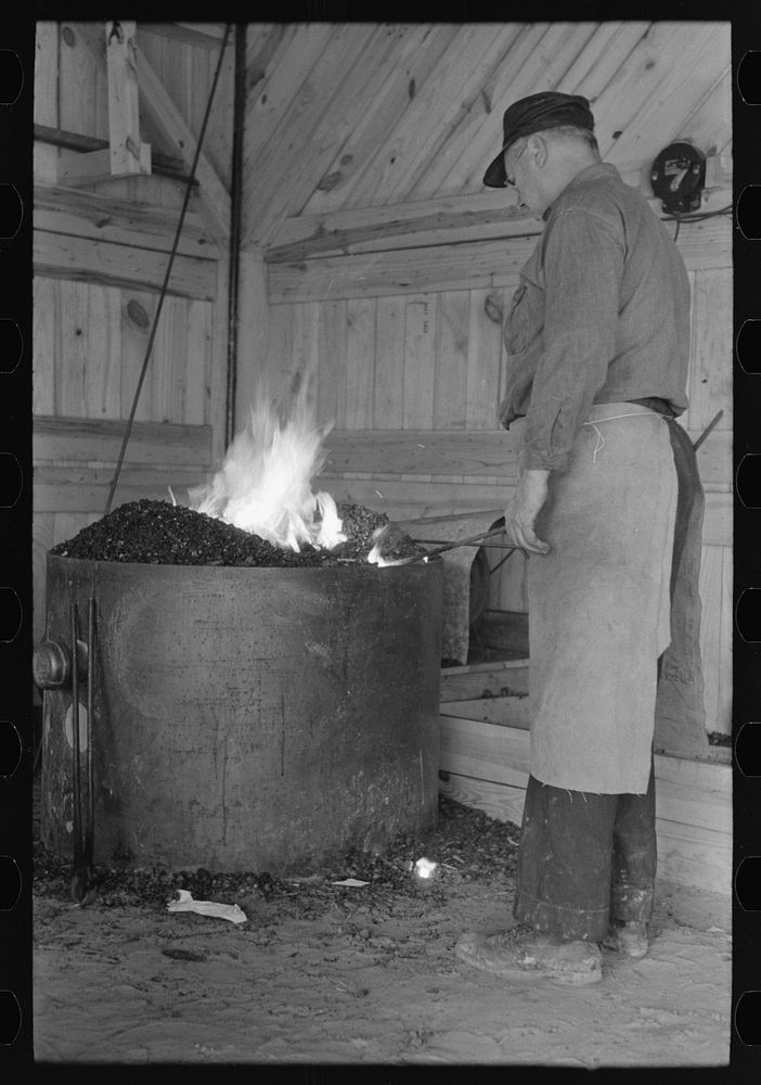 Blacksmith heating iron in forge, Southern Paper Mill construction shed, Lufkin, Texas by Russell Lee