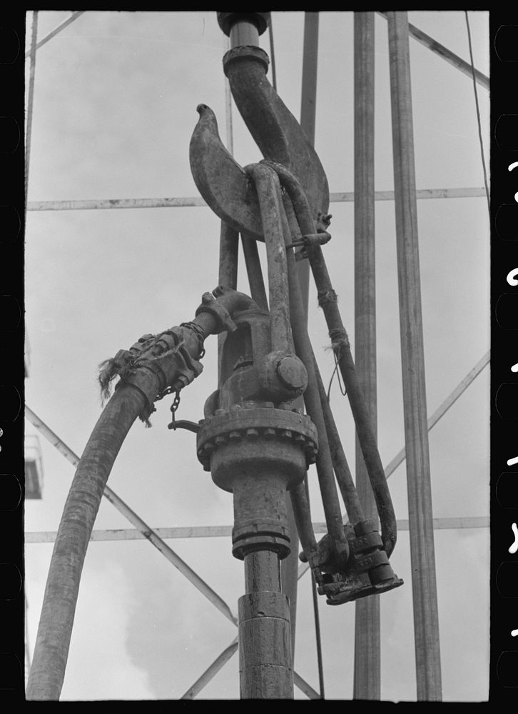 Detail of oil drilling equipment: hook of the traveling block, links and clamp of the elevator, hose connection from mud hog…