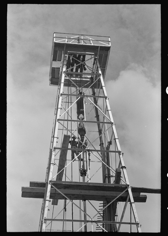 Top of derrick showing gin pole, crow's nest, crown block, traveling block, elevator and cat line. Oil well, Kilgore, Texas…