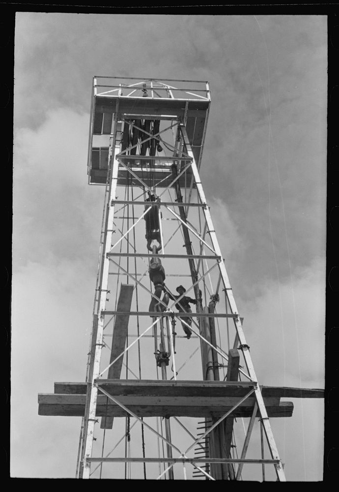 [Untitled photo, possibly related to: Top of derrick showing gin pole, crow's nest, crown block, traveling block, elevator…