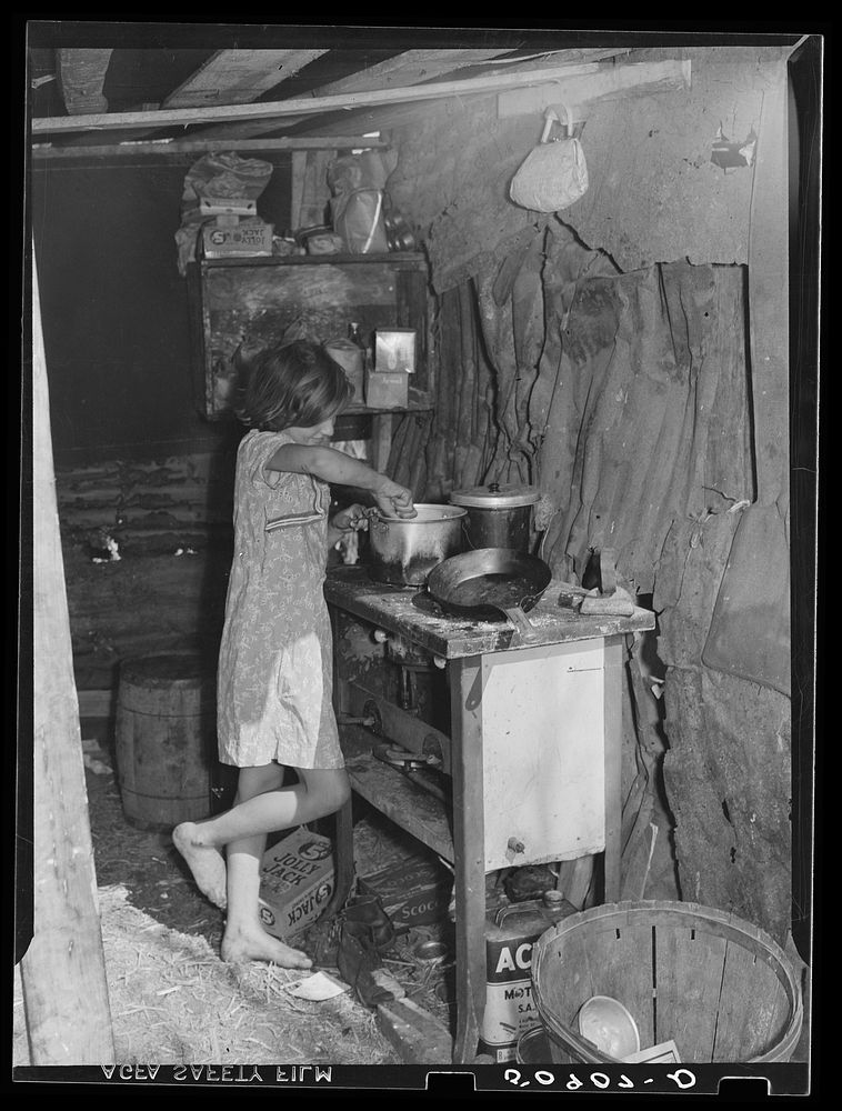 Oldest child of migrant packinghouse worker's family from Tennessee fixing supper. Her mother and father both work during…